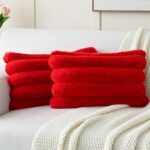 Two red faux rabbit fur throw pillow covers with a striped pattern, positioned on a neutral background.
