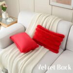 Two red faux rabbit fur throw pillow covers with a striped pattern, positioned on a neutral background.