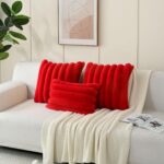 Two red faux rabbit fur throw pillow covers with a striped pattern, positioned on a neutral background.