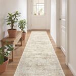 A beige/ivory Restydon 2x8 runner rug with a subtle pattern, laid out on a floor in an indoor setting.