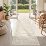 A beige/ivory Restydon 2x8 runner rug with a subtle pattern, laid out on a floor in an indoor setting.