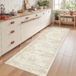 A beige/ivory Restydon 2x8 runner rug with a subtle pattern, laid out on a floor in an indoor setting.