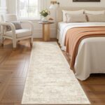 A beige/ivory Restydon 2x8 runner rug with a subtle pattern, laid out on a floor in an indoor setting.