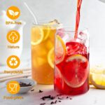 Four clear 16 oz sungwoo glass cups with bamboo lids and reusable straws, arranged neatly on a surface.