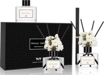 Three transparent glass bottles of WEALD TRIBE flower reed diffusers with black fiber sticks and dried flowers in a luxurious