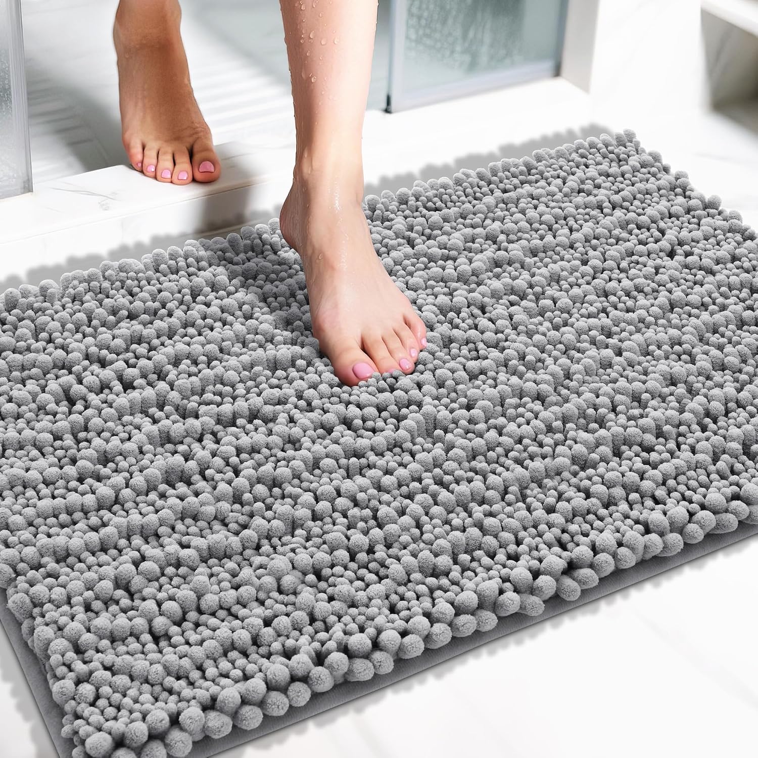 yimobra-large-36x24-inch-grey-chenille-bath-mat-non-slip-washable-quick-dry-01 A soft, rectangular grey chenille bath mat with a shaggy texture, placed on a clean bathroom floor.